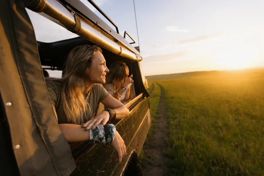 Woman leaning out safari jeep at sunset